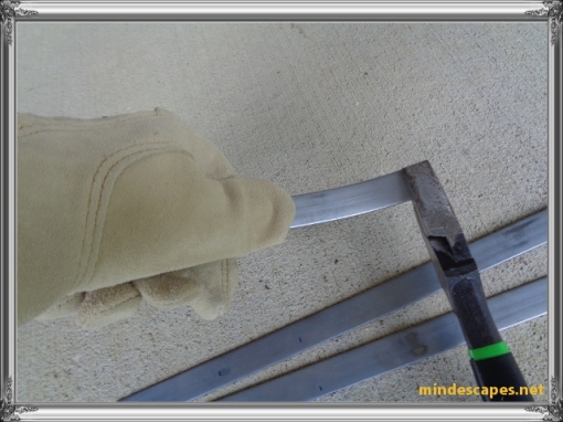 gloved hand showing using thumb to bend a curved hook from the metal strip